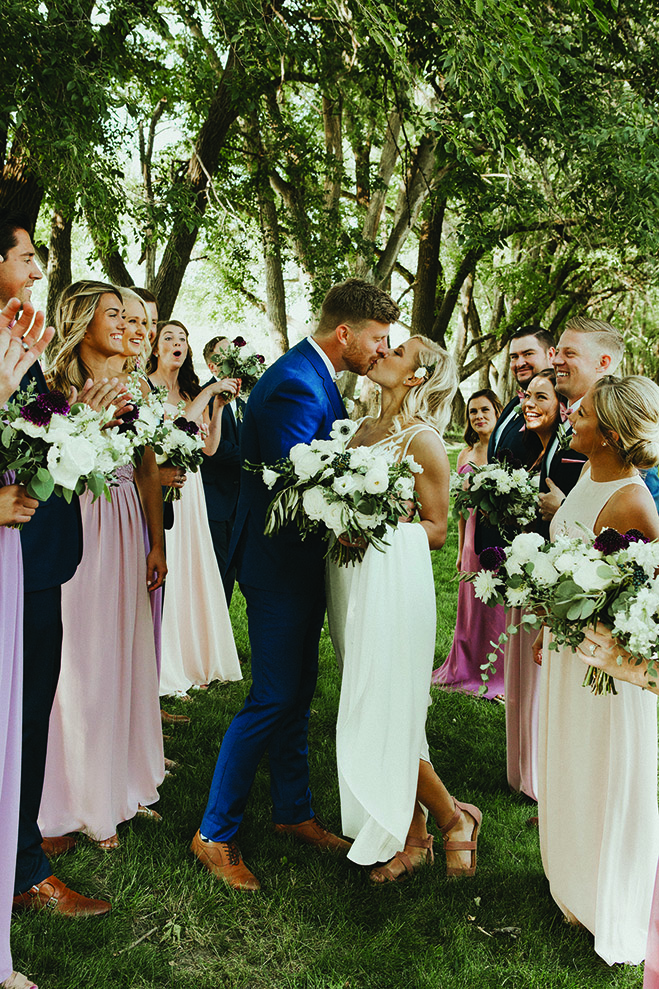 Lindsay and Hunter kiss as their wedding party looks on at Carlos Creek Winery.