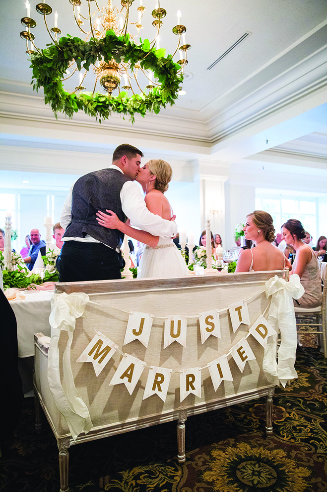 Paige and Jake kiss in front of a "Just Married" sign at their wedding reception at the Wayzata Country Club