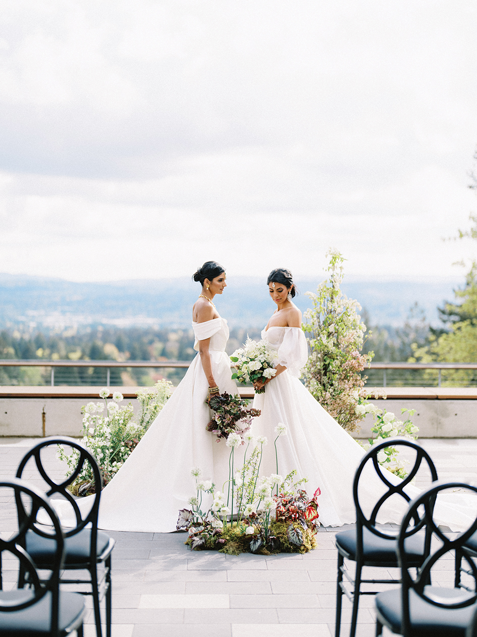Cody” by BRIDE by Sarah Seven from The Dress Theory features a traditional silhouette with a sophisticated flair due to the asymmetrical off-the-shoulder sleeve.