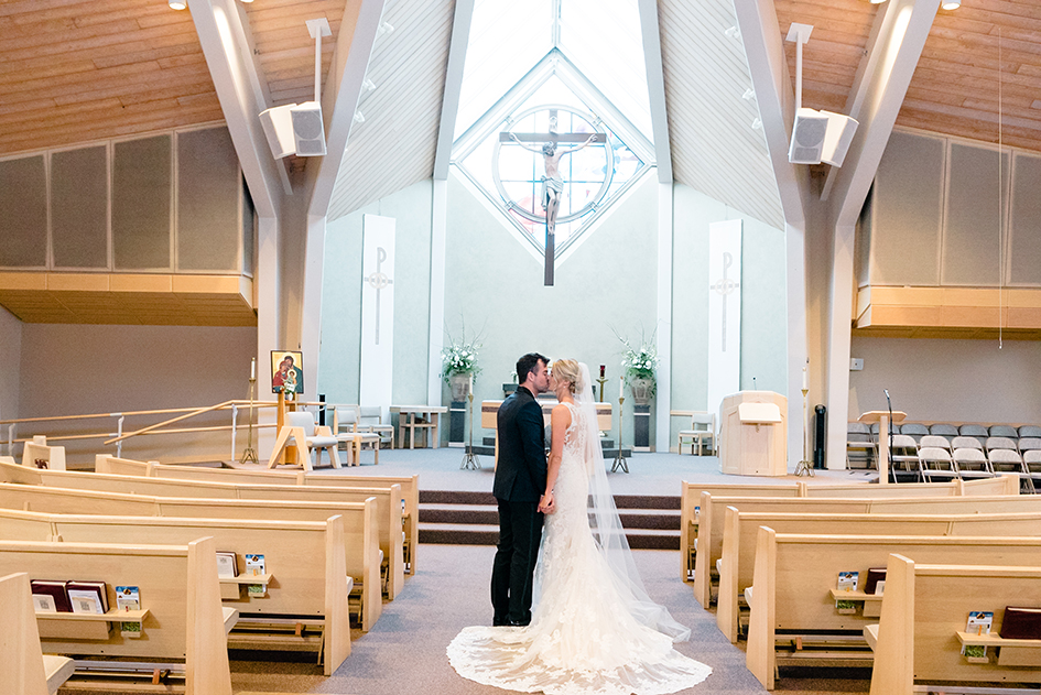 Jordan and Jenna Schiemer kiss in the aisle at their wedding.
