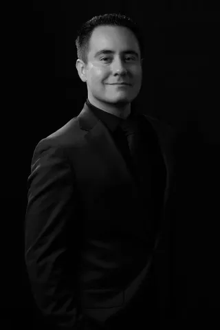 Professional black-and-white portrait of Richard Saenz of Royal Films in a suit against a dark background