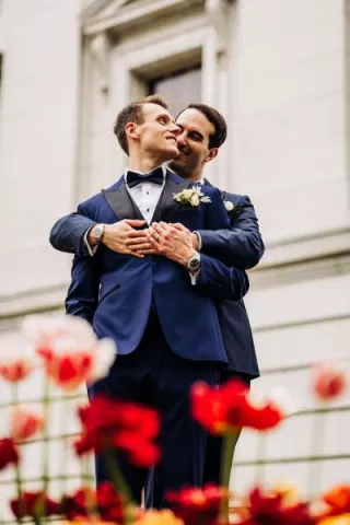 Zach and Clay Embrace Amidst the Flowers on their Wedding Day at The Madison Club