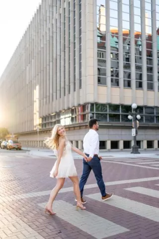 Katie and Zachary cross a street in Downtown St. Paul in their engagement photo session 