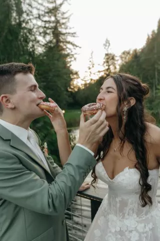 Bride and groom feed each other donuts at outdoor reception