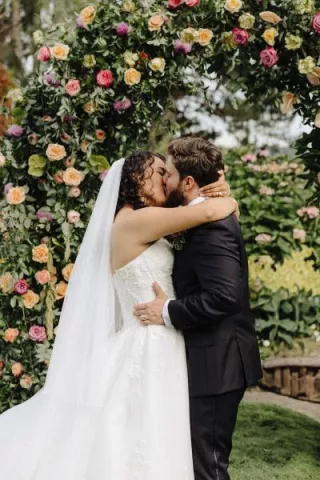 Valeria and Benjamin share a kiss at their floral-filled altar at Kiana Lodge