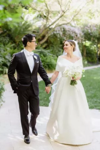 NBC Southern California newscaster Ted Chen and his bride, Ariell Kirylo, walk hand in hand through the lush gardens of Hotel Bel-Air, glowing with joy on their wedding day.