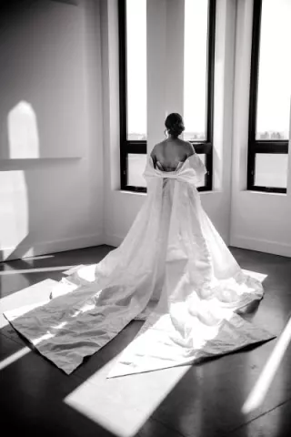 Black and white photo of model wearing gown with bow detail shawl 