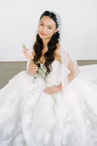 Model poses in ballgown with flowers in hand