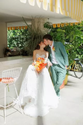 Bride and groom share a kiss sitting outside at their sunny wedding day at Parker Palm Springs