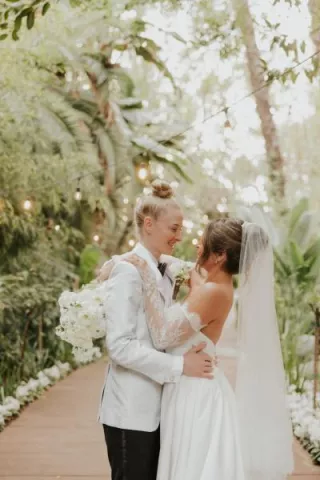 Taylor and Summer embrace on the grounds of Botanica on their wedding day