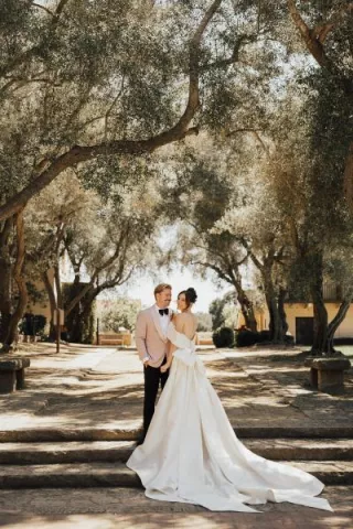 Bride and groom smile and pose, framed by trees on the grounds of The Cate School