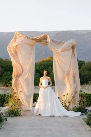 Model poses under architectural and organic altar against mountainous landscape at Topa Vista