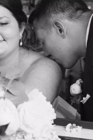 Close up of groom kissing bride's shoulder in wedding day at Mercantile Hall