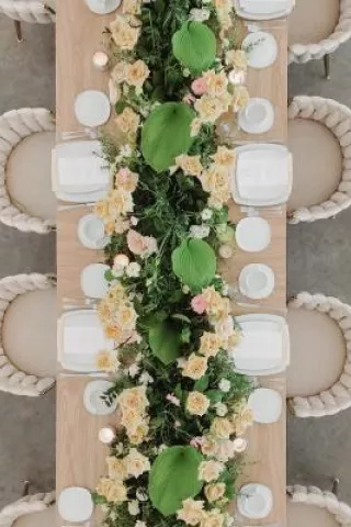 Garden wedding table featuring a long harvest table with lush greenery, soft yellow roses and apricot blooms, styled for summer wedding inspiration at The Hutton House in Minnesota