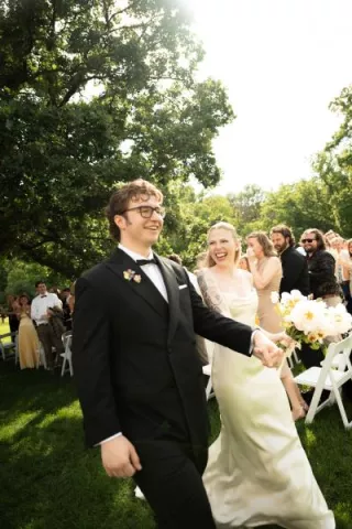 Addie and Walker beam as they walk down the aisle after exchanging I do's at Mayowood Stone Barn