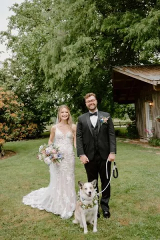 Bride and groom pose with their dog on their wedding day at Woodland Meadow Farms