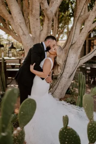 Bride and groom share romantic embrace framed by cacti