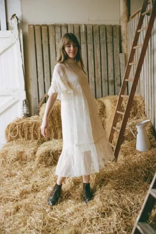 Bride in a barn wearing the Havisham dress by Joanie, a romantic Victorian-inspired wedding gown with polka-dot mesh, lace embroidery, and flounce sleeves