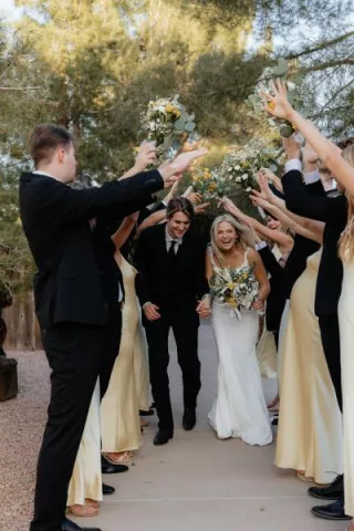 Bride and Groom run under archway created by bridal party