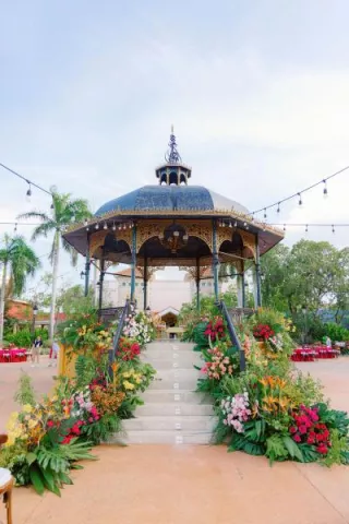 Bright and lush tropical florals line the steps of a gazebo in multicultural wedding in cancun