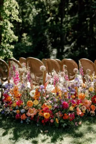 Bold abundance of blooms line the outdoor aisle in wedding day at Fox Hollow Farms