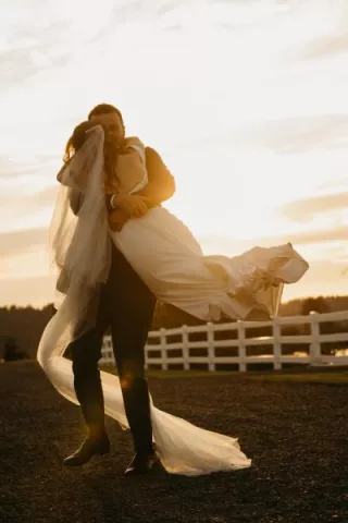 Connor picks up and twirls Katie on the grounds of Fiddler's Bluff on their wedding day