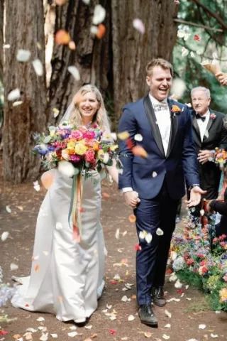 Flower Petals Thrown in the Air while Katie and Sam Walk Down the Aisle at Colorful Santa Lucia Preserve Wedding