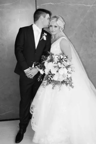 Groom kisses side of bride's head as they pose for their couple portrait outside of Venue 5 Twenty-Two