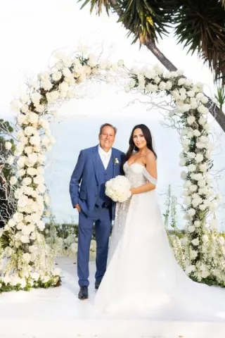 Experience the elegance of Tiana Belle and Todd Bryant’s wedding as they exchange vows at the altar, surrounded by an ethereal all-white setup and vibrant floral accents at Gulls Way.