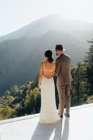 Bride and groom look out onto mountainous landscape 