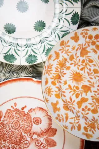 Layered fine china plates from Maison de Carine featuring floral and botanical patterns in coral, green, and orange hues—styled for the 2025 Met Gala