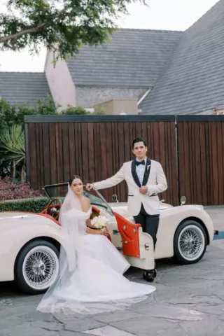 Olivia and Blaec pose in a vintage getaway car