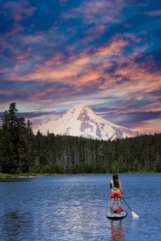 Paddle boarder on a lake with mountain in the background