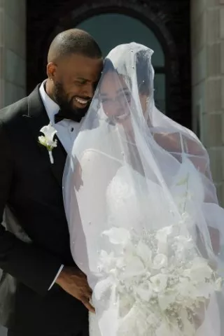 Bride and groom stand close together in an embrace on their wedding day