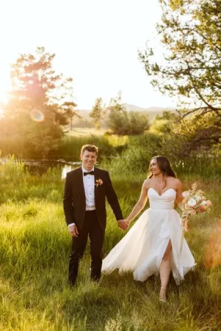 Bride and groom walk hand in hand in the golden hour light on the grounds of Sunriver Resort