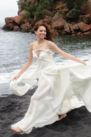 Model poses in fashion-forward wedding gown on the Black Sand Beach with Lake Superior in the background