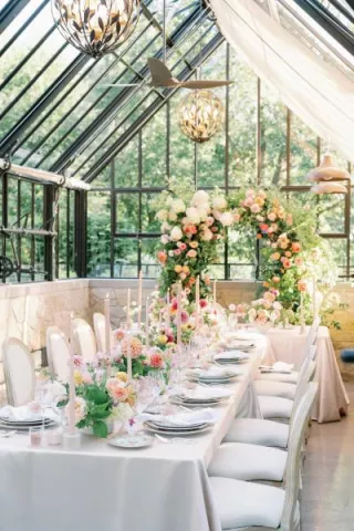 Greenhouse reception dinner featuring designer tableware and lush florals