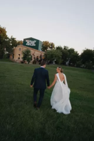 Abby and Caleb walk on the grounds of Nicollet Island Pavilion on their wedding day