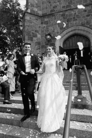 Isabel and John descend the staircase after ceremony t Plymouth Congregational Church as petals waft through the air