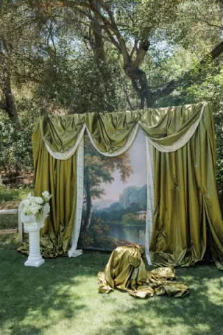 Outdoor photo-op featuring green drapery and a painted scene