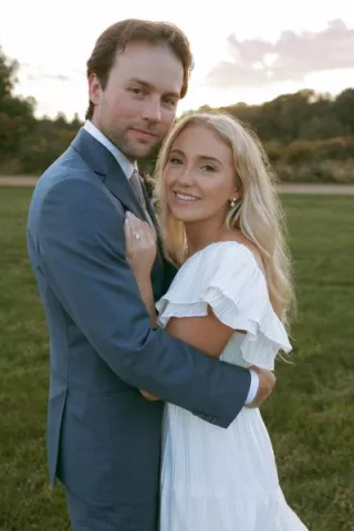 Bride and groom smile and embrace on the grounds of Rustic Roots Winery