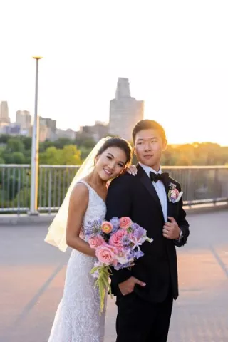 Bride and groom embrace with bright whimsical florals in hand