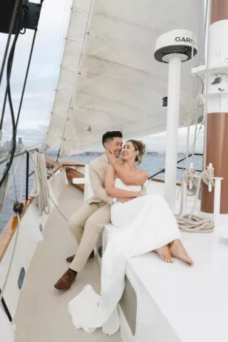 Groom holds bride in his arms on a sailboat for their welcome party