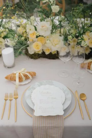 Butter yellow tablescape featuring lush florals and croissant details at Zenia