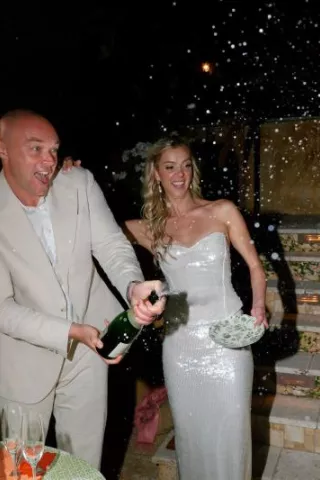 Bride and groom pop champagne at reception at groom's private residence