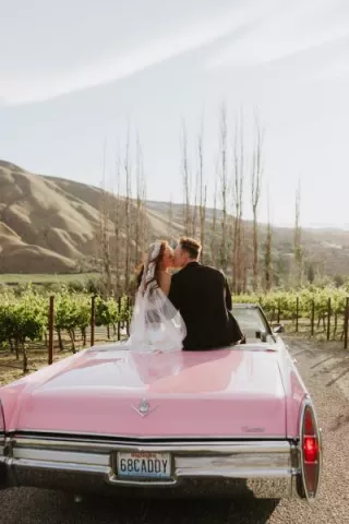Lauren and Braedon share a kiss as they sit in a classic pink cadillac convertible