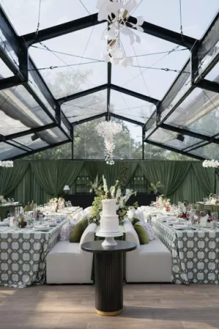 Bold maximalist reception design featuring luxe green draping and textured chandeliers at Woodland Glasshaus