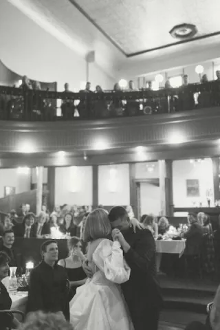Caitlin and Josh Sharing their First Dance with Friends and Family Watching from the Balcony of The Grand Event Center