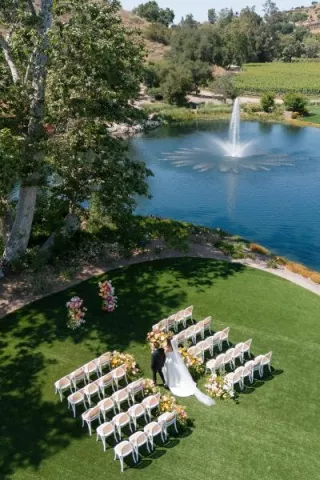 Aerial scene of models walking down aisle in outdoor ceremony featuring peachy florals on the grounds of Monserate Winery