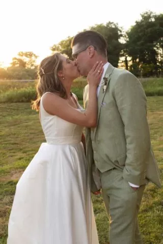 Bride and groom share a kiss during golden hour-lit reception at Hawk Creek Gallery